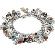 Handcrafted silver charm bracelet honoring Native American heritage, featuring artwork under glass cabochons of tribal elders, warriors, and wildlife. Includes engraved tags with phrases like ‘Respect the Earth and all Souls,’ ‘Walk in Balance on Your Path,’ and ‘Honor the Teachings of the Elders.’ Embellished with brown goldstone beads, turquoise-blue Austrian crystals, and charms like feathers, eagles, and peace pipes. Displayed on a white background.