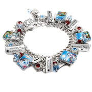 Handcrafted silver charm bracelet inspired by Greece, featuring scenic travel imagery under glass cabochons including Santorini sunsets, Athens landmarks, the Aegean Sea, and Mykonos. Includes engraved travel tags with sayings like ‘I Love Greece,’ ‘Adventure in Athens,’ and ‘My Heart is in Mykonos.’ Embellished with red and blue Austrian crystals, suns, sailboats, and Grecian symbols. Displayed on a white background.