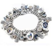 Silver New Year’s Eve charm bracelet featuring celebration-themed charms including champagne glasses, fireworks, clocks, and party hats. Includes glass cabochons with festive art, engraved tags like “Pop the Bubbly” and “Midnight Magic,” and is accented with gold and silver Austrian crystals. Displayed on a white background.