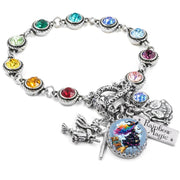 Handcrafted silver charm bracelet featuring a colorful rainbow witch flying on a broomstick, with whimsical fantasy artwork under a glass cabochon. Includes engraved tag reading ‘Rainbow Magic,’ a silver flying witch, a wand, and vibrant rainbow-colored Austrian crystals set around the bracelet. Displayed on a white background.