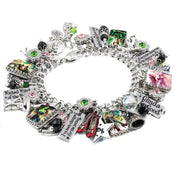 Handcrafted silver charm bracelet inspired by Wicked and The Wizard of Oz, featuring detailed charms of Elphaba, Glinda, ruby slippers, a tornado, and flying monkeys. Includes artwork under glass cabochons, engraved tags with sayings like ‘I’ve Been Changed for Good,’ ‘Wicked Witch of the West,’ and ‘Everyone Deserves the Chance to Fly.’ Embellished with pink, green, and black Austrian crystals. Displayed on a white background.