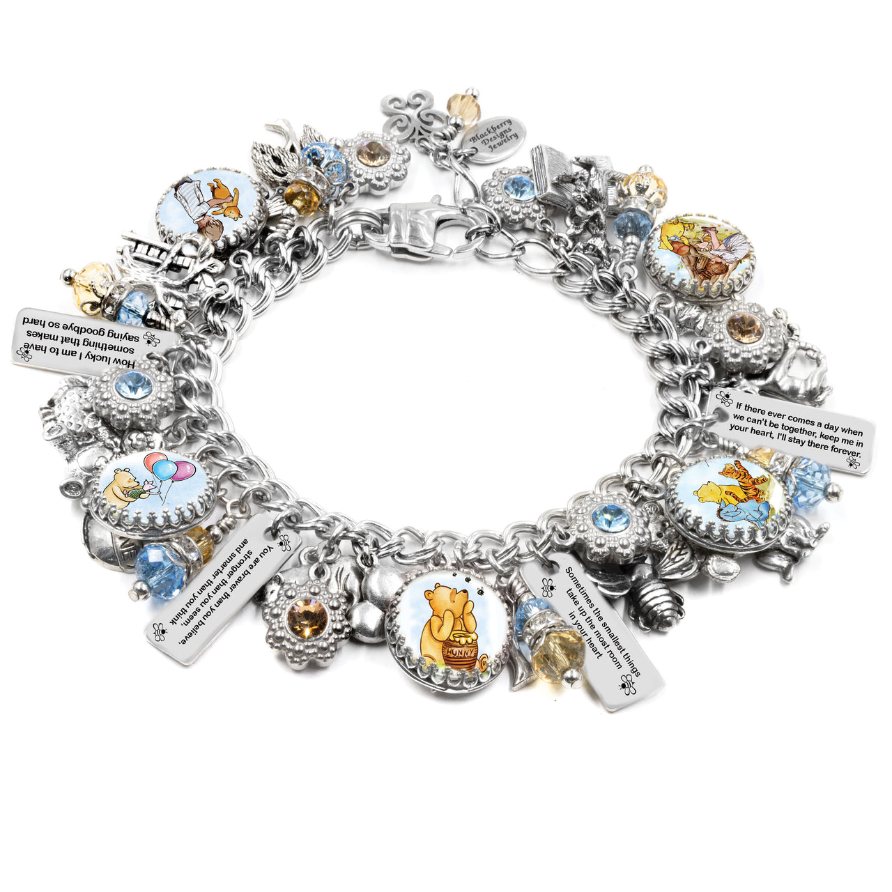 Silver charm bracelet inspired by Winnie the Pooh quotes, featuring classic book-style artwork under glass cabochons, engraved tags with beloved quotes like “You are braver than you believe” and “Forever & Always,” accented with gold and red Austrian crystals, and charms including honey pots, bees, and woodland leaves. Displayed on a white background.