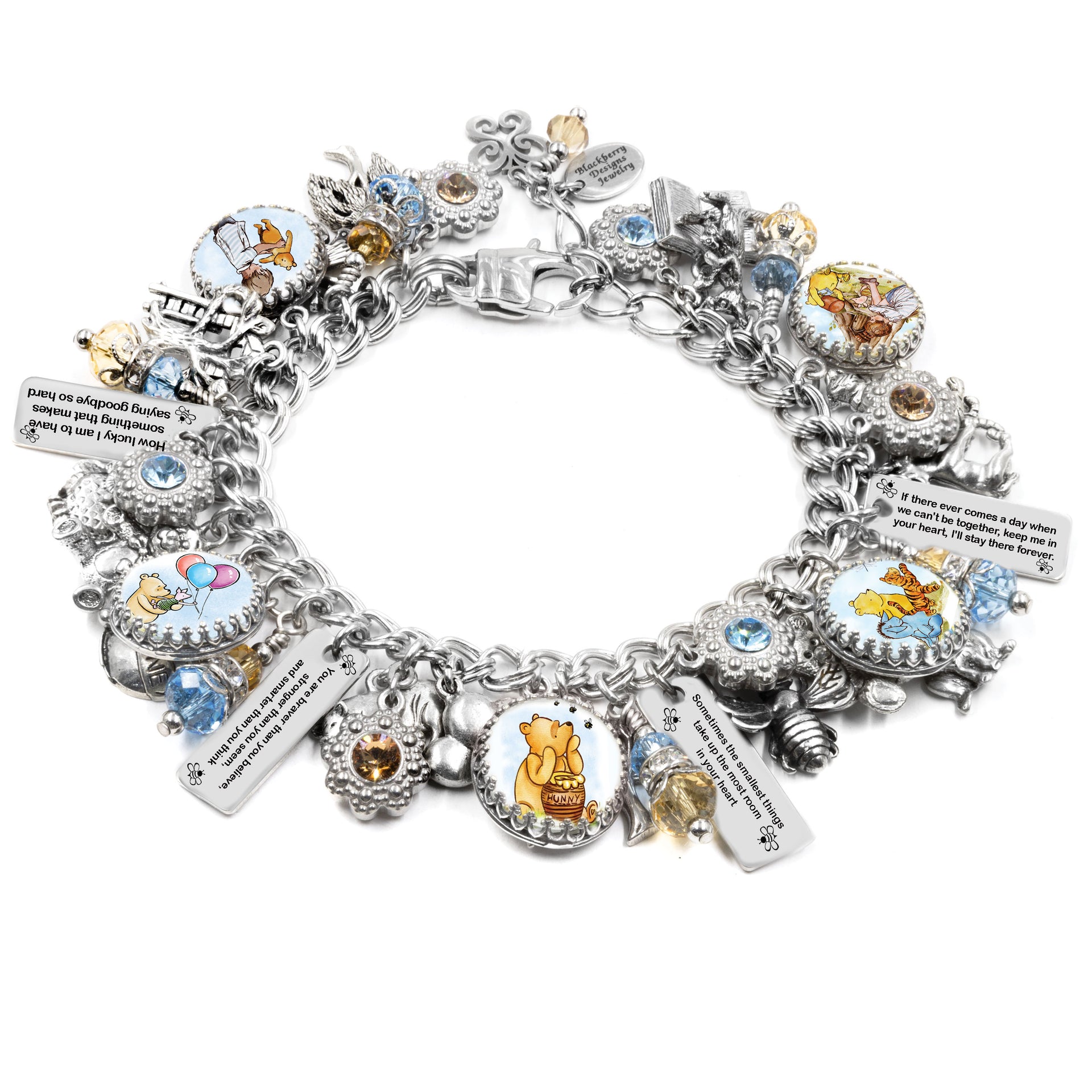 Silver charm bracelet inspired by Winnie the Pooh quotes, featuring classic book-style artwork under glass cabochons, engraved tags with beloved quotes like “You are braver than you believe” and “Forever & Always,” accented with gold and red Austrian crystals, and charms including honey pots, bees, and woodland leaves. Displayed on a white background.