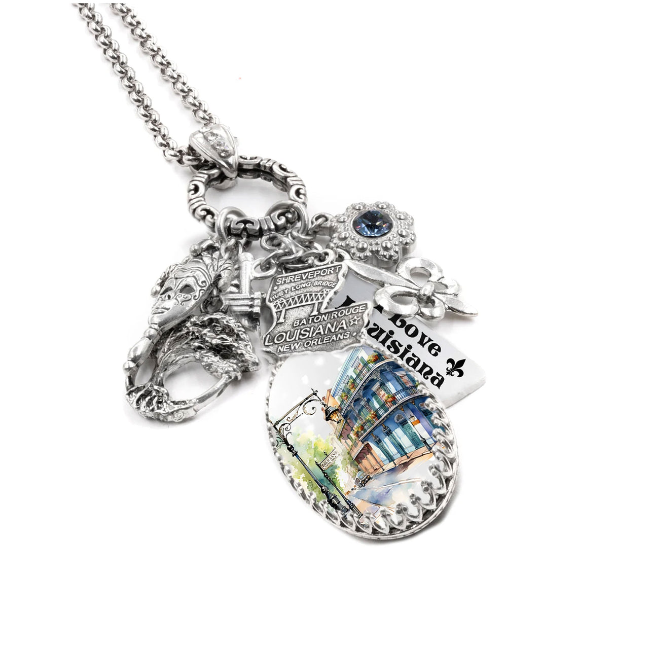 Silver charm necklace inspired by Louisiana, featuring state icons like the fleur-de-lis, alligator, and steamboat, accented with blue and gold crystals, a detailed Louisiana state map charm, and engraved tags like “Bayou Belle” and “French Quarter Flair.”