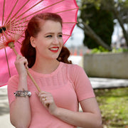 woman holding pink umbrella wearing cat charm bracelet