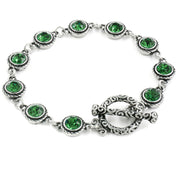 A silver bracelet adorned with green gemstones, featuring a clasp and a decorative element.