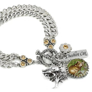 A silver-toned bracelet with a charm featuring a cat and a tree, as well as a charm with the text "Cheshire Cat".
