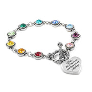 A silver bracelet with a heart-shaped charm attached, featuring a variety of colorful gemstones.