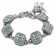 A silver-toned bracelet adorned with colorful gemstones, including blue, green, and purple stones, and a charm at the end.