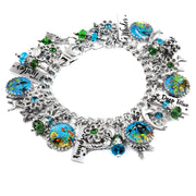 A silver bracelet adorned with various charms, including a blue and green design, a starfish, and a seashell. The bracelet also features a charm that says "Dive Blue" and another that says "Whales".