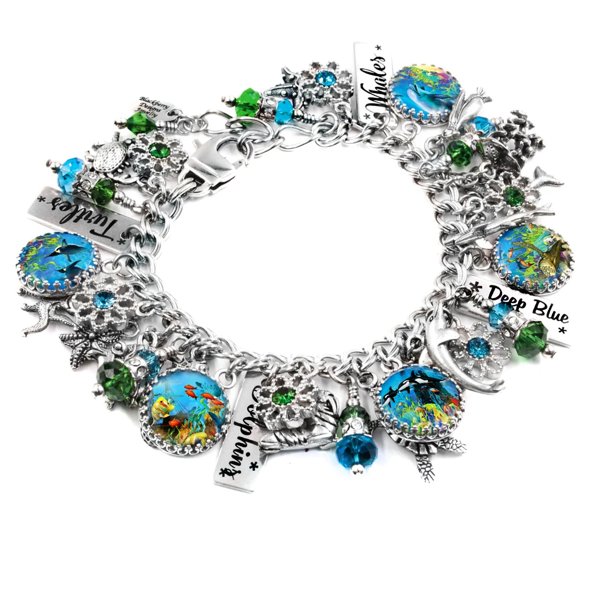 A silver bracelet adorned with various charms, including a blue and green design, a starfish, and a seashell. The bracelet also features a charm that says "Dive Blue" and another that says "Whales".