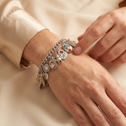 A close-up image of a person's hand wearing a bracelet with various charms and charms attached to it.