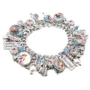 A silver charm bracelet adorned with various charms, including a heart-shaped charm, a bird charm, and a crystal charm. The bracelet also features a charm with a picture of a woman and the word "Blessings".