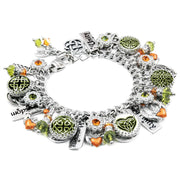 A silver-toned charm bracelet adorned with various charms, including a heart-shaped charm, green and orange gemstones, and other decorative elements.