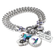 A silver-toned charm bracelet with various charms, including a bird charm, a flower charm, and a small bird charm. The bracelet also has a charm that says "Let your spirit soar!"