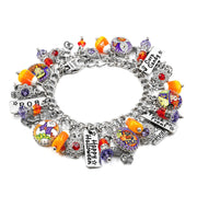 A silver charm bracelet featuring multiple Halloween-themed charms, including candy corn, a pumpkin, a 'Happy Halloween' tag, a 'Trick or Treat' sign, and purple beads, displayed on a clean white background.