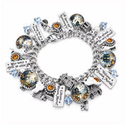 A silver charm bracelet featuring various Halloween-themed charms, including ghosts, haunted houses, keys, and text plaques, with clear and orange gemstones, displayed on a white background.