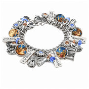 A silver charm bracelet featuring multiple religious-themed charms, including a nativity scene, a cactus with a handprint, and text charms reading 'Peace on earth, Frankincense gold and myrrh, birth of christ, nativity, away in a manager. The bracelet is displayed on a clean white background.