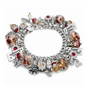 A silver-toned Christmas charm bracelet featuring multiple dangling ornaments, including red and amber glass beads, clear rhinestone accents, and three engraved nameplates reading Santa Claus, Saint Lucia, and Saint Lasas.