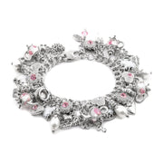A silver-toned charm bracelet featuring various whimsical charms, including a teapot, skull, crescent moon, and pink gemstone accents, displayed on a clean white background.