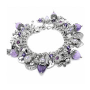A silver charm bracelet featuring various gothic and occult-themed charms, including a skull, crossbones, pentacle, and key, embellished with purple faceted gemstones, set against a plain white background.