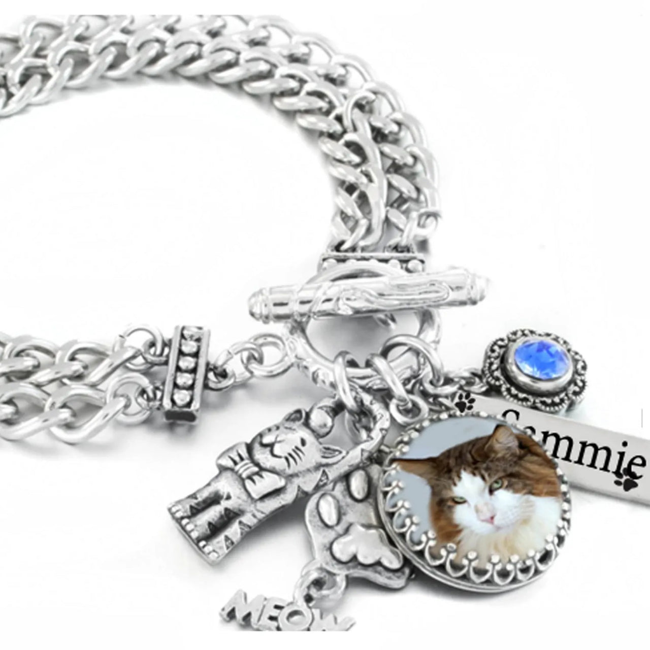 A silver-toned charm bracelet with various charms, including a cat charm, a small figurine, and a blue gemstone.