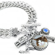 A silver-toned charm bracelet with various charms, including a cat charm, a small figurine, and a blue gemstone.