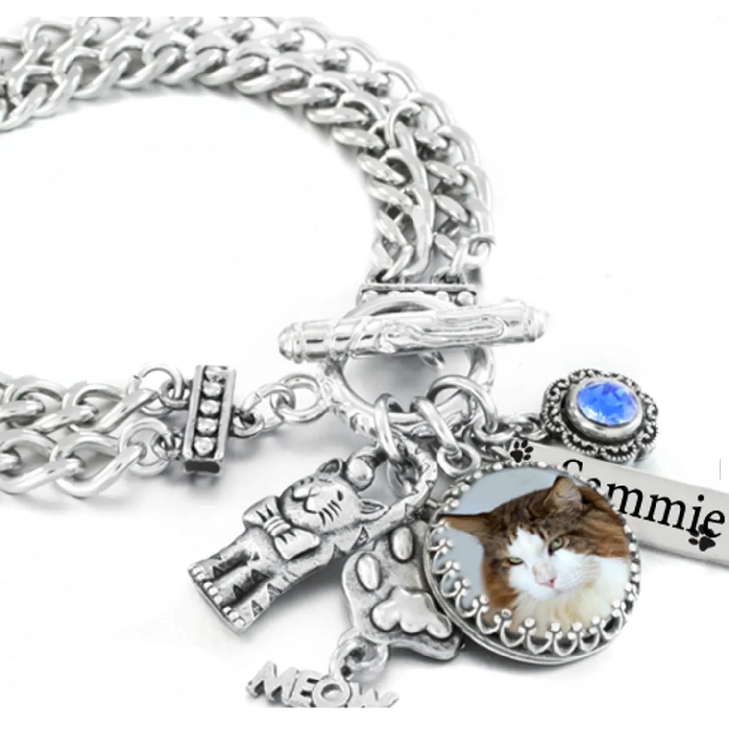 A silver-toned charm bracelet with various charms, including a cat charm, a small figurine, and a blue gemstone.