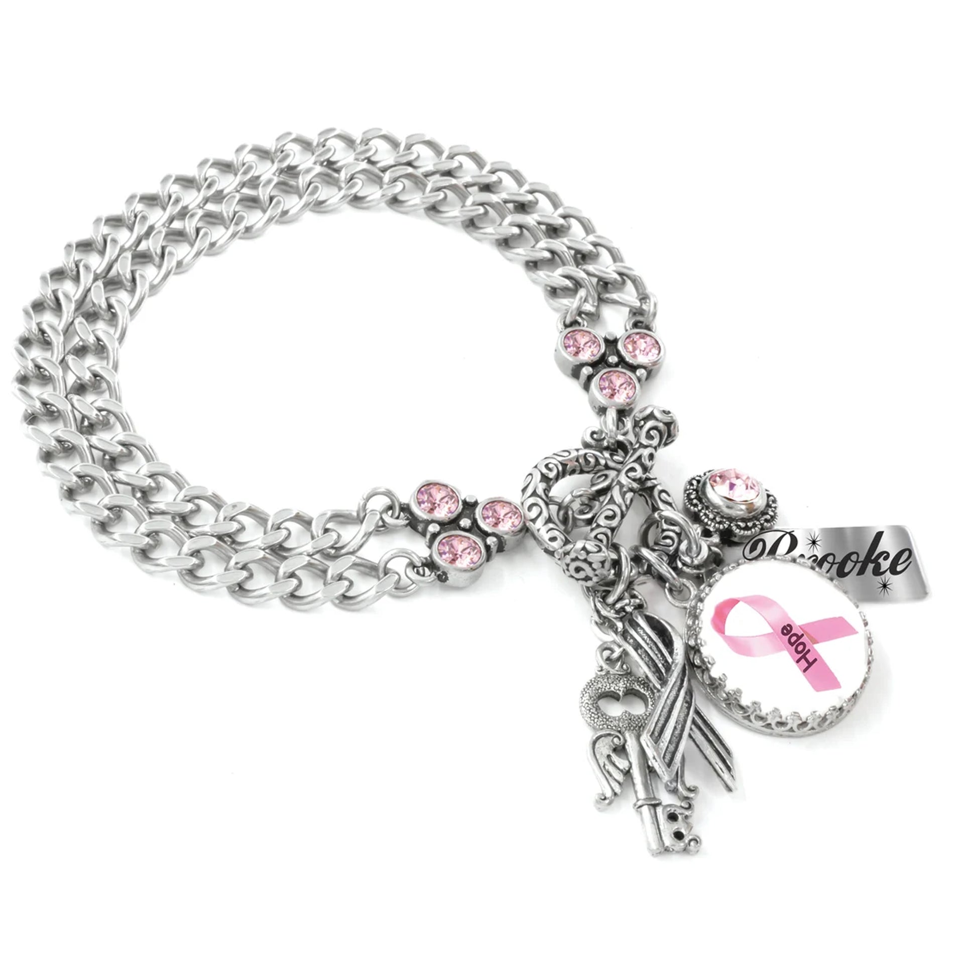 A silver-toned charm bracelet with various charms, including a key, a ribbon, and a pink ribbon symbol, as well as a charm that says "Dove".