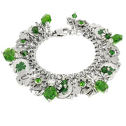 A silver-toned charm bracelet adorned with various charms, including green gemstones, clovers, and other decorative elements.